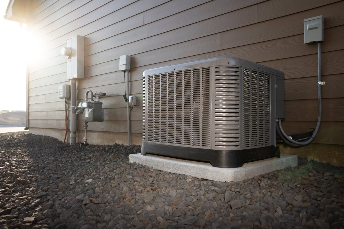 Modern HVAC air conditioner unit on concrete slab outside of duplex house