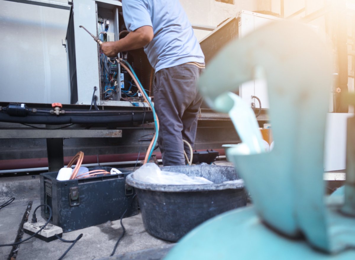 Refrigeration technician welding industrial HVAC refrigerant pipes