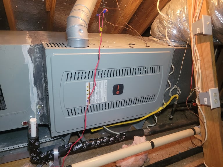 HVAC system equipment installed in attic with metal ductwork, wiring, and insulation surrounding it